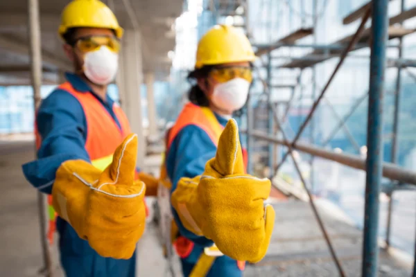 Two construction workers wearing yellow and blue gloves.